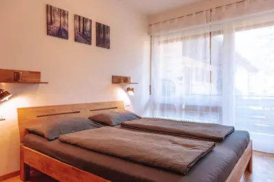 a bed in a bedroom with a large window at Pool House Merano in Merano