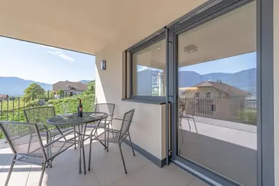 a patio with a table and chairs on a balcony at Stürz Ferienwohnungen in Termeno