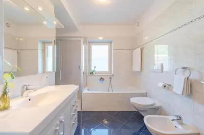 a bathroom with two sinks and a tub and a toilet at Stürz Ferienwohnungen in Termeno