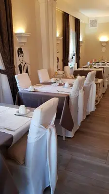 a row of tables in a room with white chairs at Garni Villa Tyrol - Adults Only in Merano