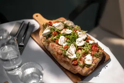 a pizza on a wooden cutting board on a table at Pension Höfler - Fernblick in Schenna