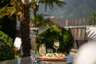 a table with a pizza and two glasses of wine at Pension Höfler - Fernblick in Schenna