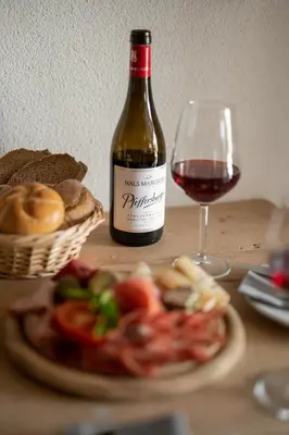 a bottle of wine and a plate of food and a glass at Pension Höfler - Fernblick in Schenna