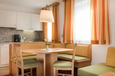 a kitchen with a wooden table with chairs and a table at Pension Höfler - Fernblick in Schenna