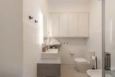 a white bathroom with a toilet and a sink at Lauben Apartment Bolzano in Bolzano