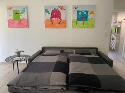 a bed in a bedroom with three paintings on the wall at Neu, zentral, sonnig, Garage inklusive in Merano