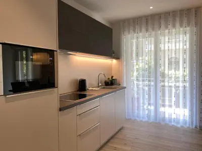 a kitchen with white cabinets and a sink and a window at Neu, zentral, sonnig, Garage inklusive in Merano
