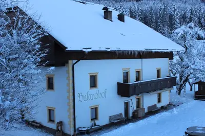 a building with a sign on it in the snow at Ferienwohnungen Bulandhof in Valdaora