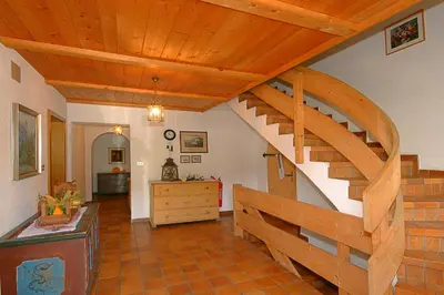 a living room with a wooden spiral staircase at Ferienwohnungen Bulandhof in Valdaora