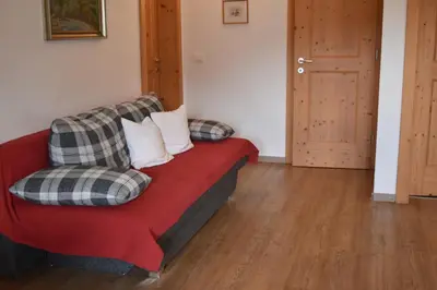 a red couch with pillows on it in a room at Ferienwohnungen Bulandhof in Valdaora