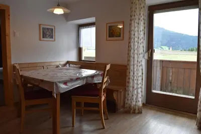 a dining room with a table and chairs and a window at Ferienwohnungen Bulandhof in Valdaora
