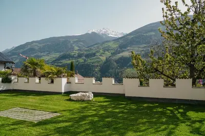 a garden with a fence and a mountain in the background at Oberwirtshof in Rifiano