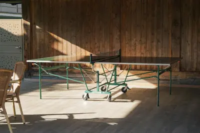 a ping pong table in a room with a chair at Oberwirtshof in Rifiano