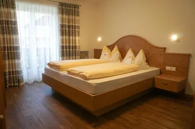 a bedroom with a large bed with a wooden headboard at Oberwirtshof in Rifiano