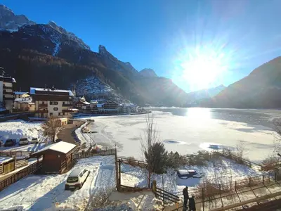 a view of a river with snow on the ground at Hotel TEA DOLOMITI - Lago di Alleghe - Monte Civetta in Alleghe