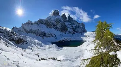 a mountain with a lake in the snow at Hotel TEA DOLOMITI - Lago di Alleghe - Monte Civetta in Alleghe