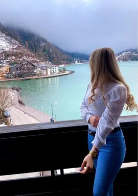 a woman standing on a balcony looking at the water at Hotel TEA DOLOMITI - Lago di Alleghe - Monte Civetta in Alleghe