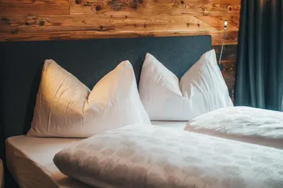 two white pillows on a bed with a wooden headboard at Aparthotel Bacher in Bressanone