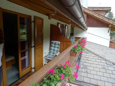 a balcony of a house with flowers and a chair at Steinerhof in Braies