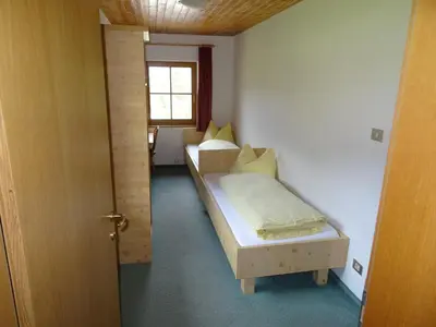 a small room with two beds and a window at Steinerhof in Braies