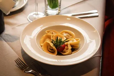 a bowl of pasta with a tomato on a table at Steinerhof in Braies