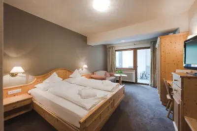 a hotel room with a large bed and a television at Hotel Tyrol in Schenna