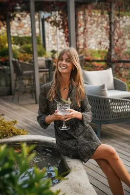 a woman sitting next to a fountain holding a wine glass at Hotel Tyrol in Schenna