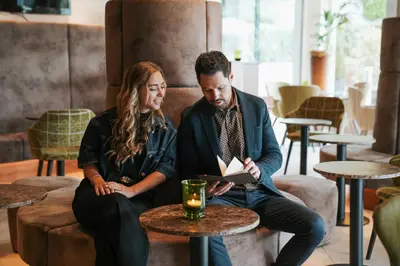 a man and a woman sitting on a couch with a table at Hotel Tyrol in Schenna