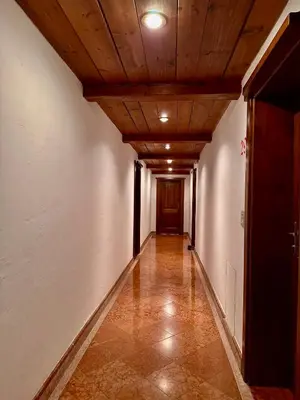 an empty corridor with a wooden ceiling and a hallway with a door at Harmony Apartment 31 in San Martino di Castrozza