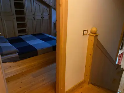 a small bedroom with a bed and a stairway at Precumon 16/5 in Arabba