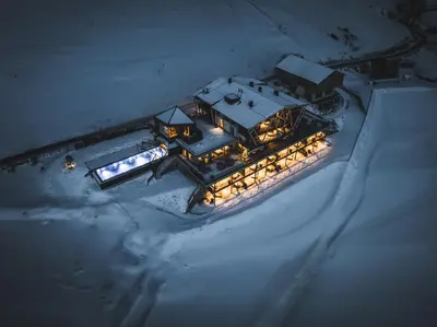 an aerial view of a house with lights in the snow at Aparthotel My Daum in Nova Ponente