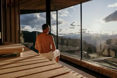 a man sitting on the edge of a building looking out at the mountain at Aparthotel My Daum in Nova Ponente