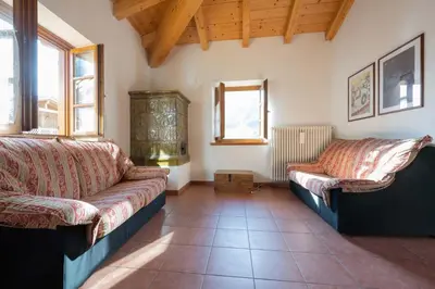 a living room with two couches and two windows at Cesa Meida 3 in Pozza di Fassa