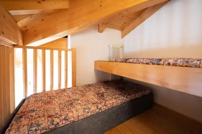 two bunk beds in a room with wooden ceilings at Cesa Meida 3 in Pozza di Fassa