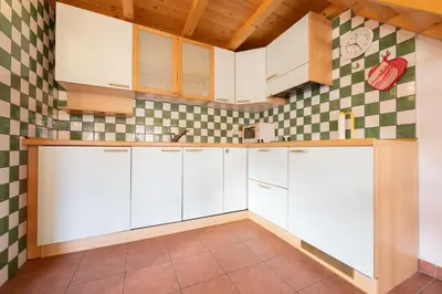 a kitchen with white cabinets and a checkered wall at Cesa Meida 3 in Pozza di Fassa
