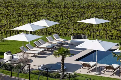 a group of chairs and umbrellas next to a pool at Ansitz Battisti Suites in Caldaro
