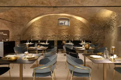 a restaurant with tables and chairs and a stone wall at Ansitz Battisti Suites in Caldaro