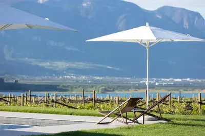 a couple of chairs and an umbrella next to a pool at Ansitz Battisti Suites in Caldaro