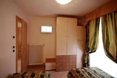 a bedroom with a bed and a cabinet and a window at Ciasa Rasom in Pozza di Fassa