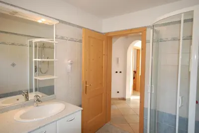 a bathroom with a sink and a glass shower at Ciasa Rasom in Pozza di Fassa