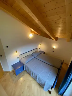 a bedroom with a bed and a wooden ceiling at Ciasa Rasom in Pozza di Fassa