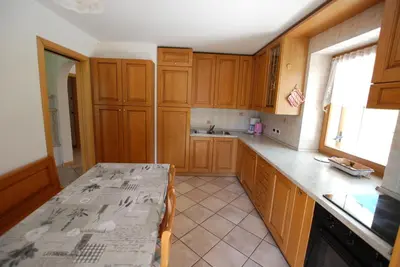 a kitchen with wooden cabinets and a table in it at Ciasa Rasom in Pozza di Fassa