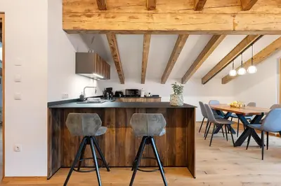 a kitchen with a wooden island with bar stools at Alpin Chalet Samer Apt Fürstenblick in Sarntal