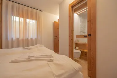 a bedroom with a bed and a bathroom with a mirror at Casa Betulla in Cortina dʼAmpezzo