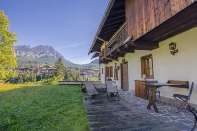 a patio of a house with chairs and a table at Casa Betulla in Cortina dʼAmpezzo