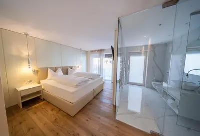 a bedroom with a bed and a glass wall at Villa Carolina in Selva di Val Gardena