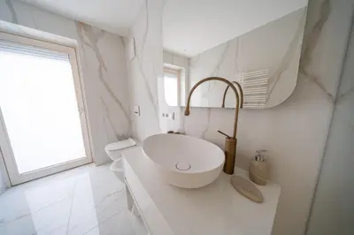 a white bathroom with a sink and a window at Villa Carolina in Selva di Val Gardena