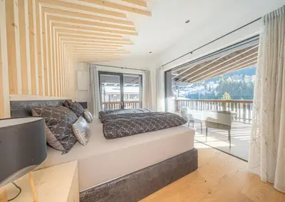 a bedroom with a bed and a balcony at Villa Carolina in Selva di Val Gardena