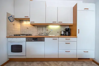 a kitchen with white cabinets and a stove top oven at Apartments Vintlana in Selva