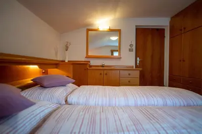 a bedroom with two beds with a mirror and a dresser at Apartments Vintlana in Selva
